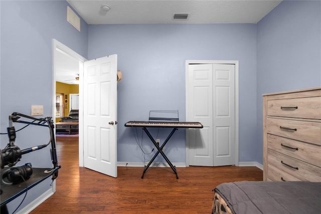 bedroom with a closet, visible vents, baseboards, and wood finished floors