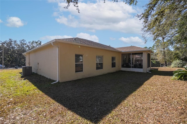 rear view of house featuring stucco siding, a lawn, central AC, and a sunroom