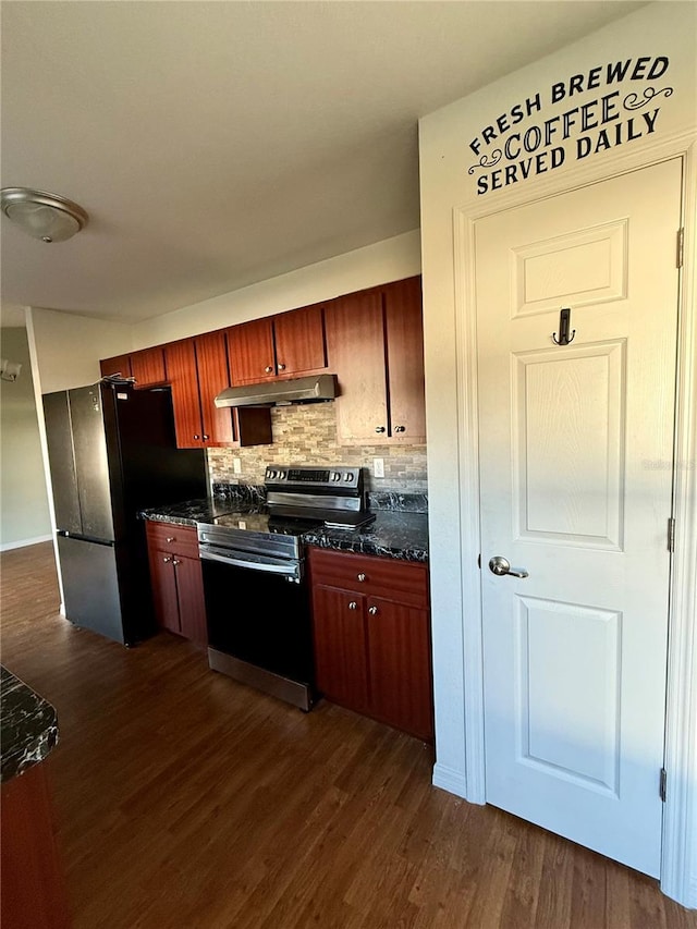 kitchen featuring under cabinet range hood, stainless steel electric stove, dark countertops, freestanding refrigerator, and dark wood-style flooring