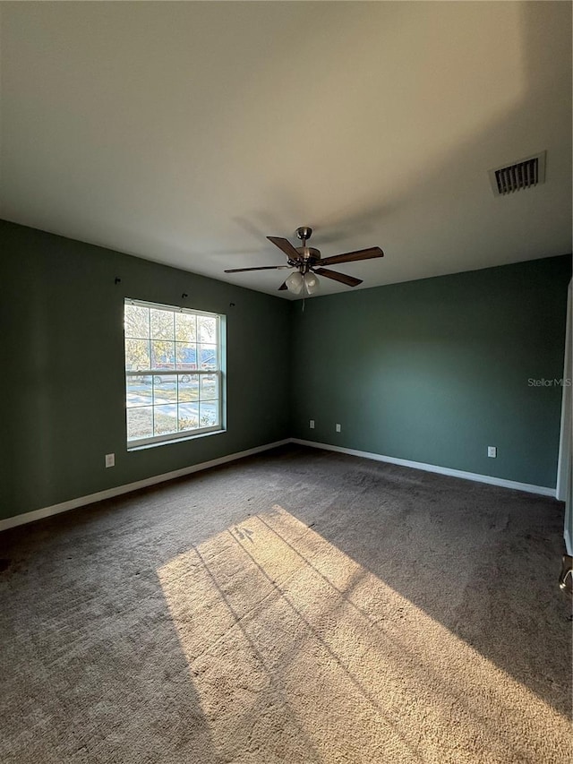 carpeted spare room featuring visible vents, a ceiling fan, and baseboards