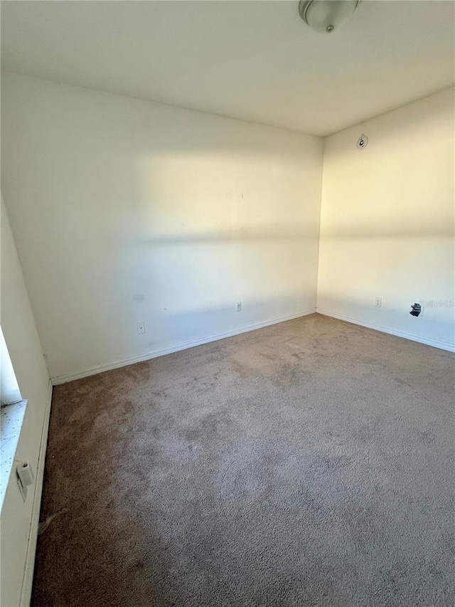 unfurnished room with baseboards and carpet flooring