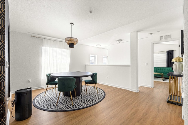 dining room featuring visible vents, a textured ceiling, and wood finished floors