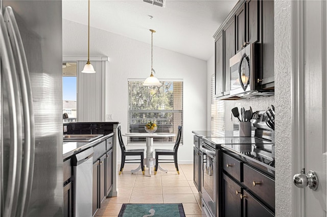 kitchen with dark brown cabinets, lofted ceiling, hanging light fixtures, appliances with stainless steel finishes, and light tile patterned flooring