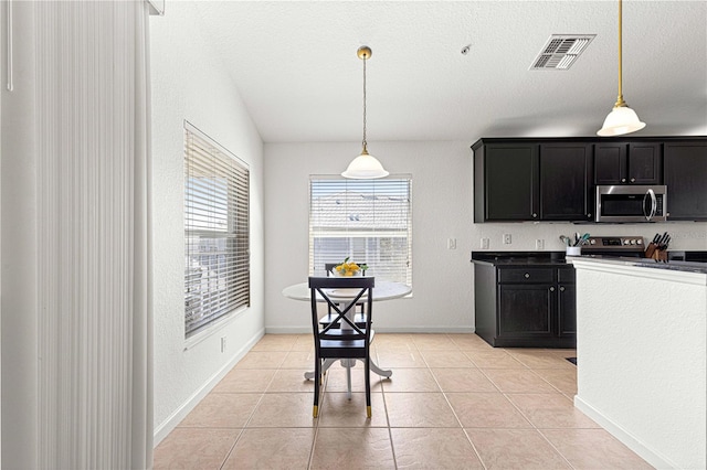 kitchen featuring visible vents, pendant lighting, light tile patterned floors, dark cabinetry, and stainless steel appliances