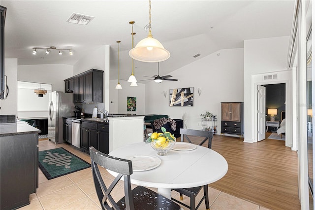 dining space with light tile patterned floors, a ceiling fan, visible vents, and high vaulted ceiling