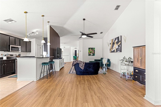 living room with light wood-type flooring, visible vents, and high vaulted ceiling