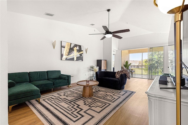 living room with vaulted ceiling, wood finished floors, visible vents, and ceiling fan