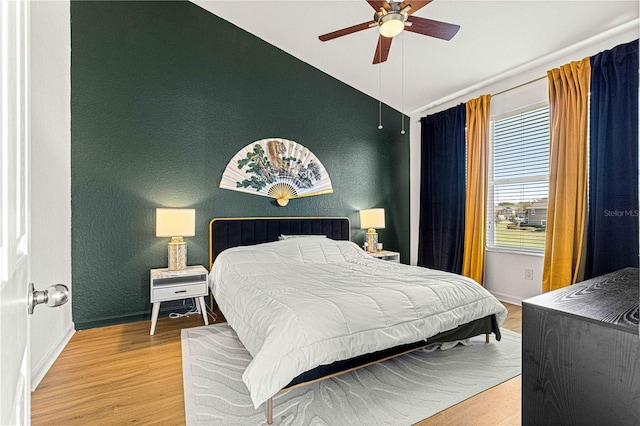 bedroom featuring lofted ceiling, wood finished floors, baseboards, and ceiling fan