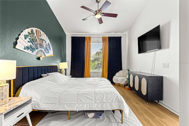 bedroom featuring a ceiling fan, wood finished floors, baseboards, and a textured wall