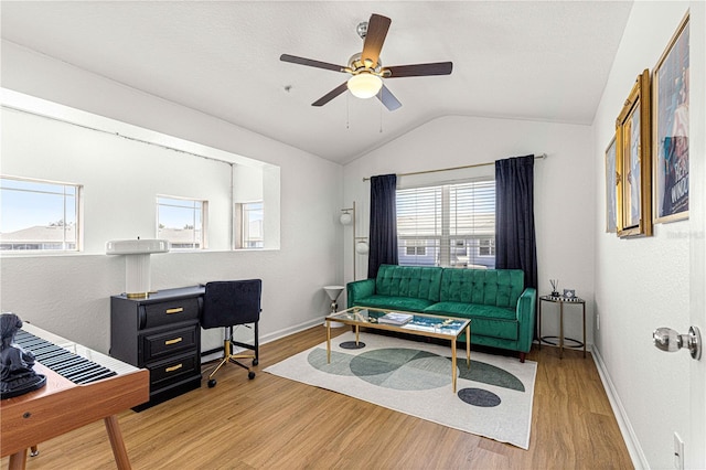 living area with ceiling fan, wood finished floors, baseboards, and vaulted ceiling