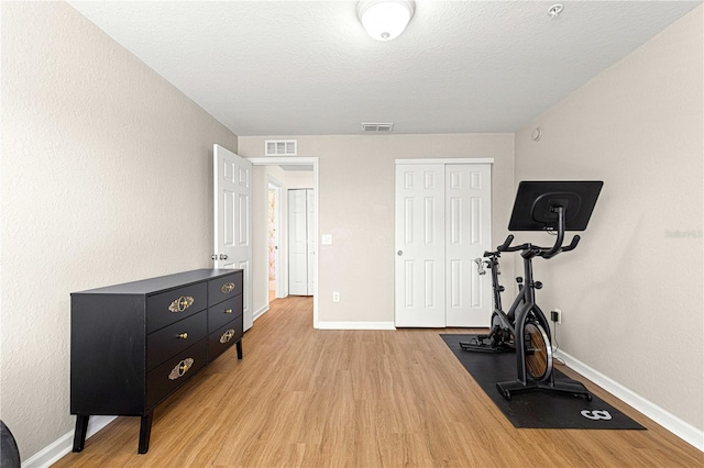 exercise room featuring baseboards, visible vents, and light wood-type flooring