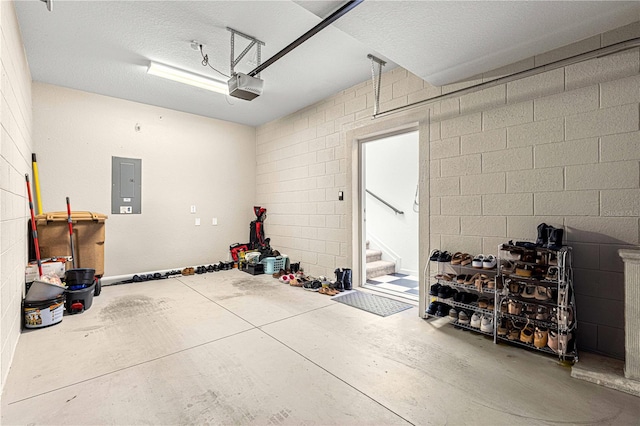 garage with electric panel, concrete block wall, and a garage door opener