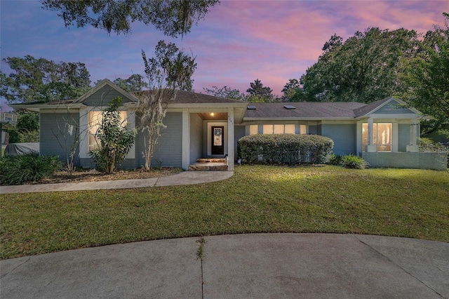 single story home with brick siding and a lawn