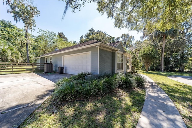 view of side of property featuring fence, concrete driveway, a garage, a lawn, and brick siding