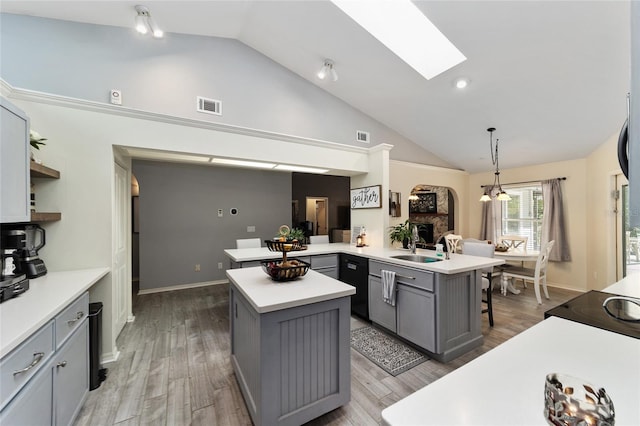 kitchen with visible vents, a peninsula, gray cabinetry, light countertops, and a center island