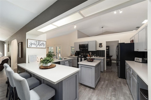 kitchen with a kitchen island, a sink, electric range oven, gray cabinetry, and stainless steel microwave