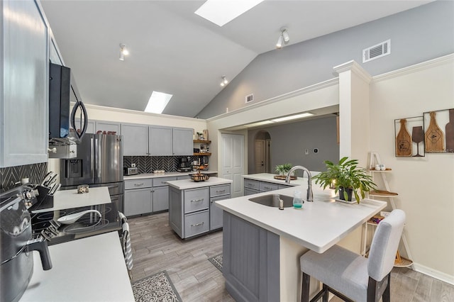 kitchen featuring visible vents, gray cabinetry, black microwave, a peninsula, and a sink