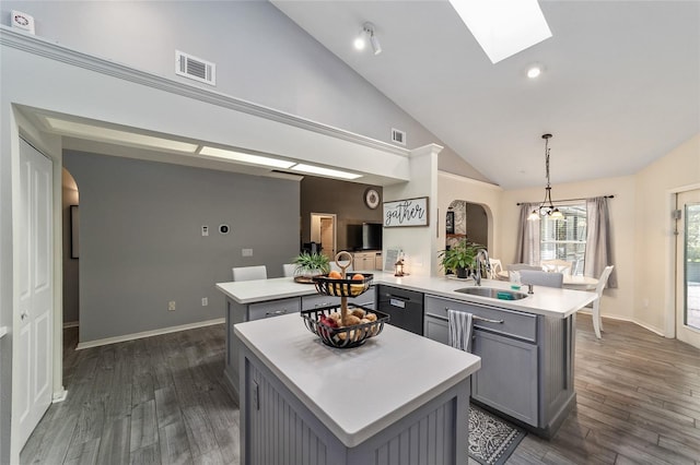 kitchen featuring visible vents, gray cabinetry, a peninsula, arched walkways, and a sink