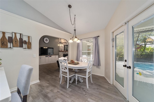 dining area featuring arched walkways, french doors, wood finished floors, and vaulted ceiling