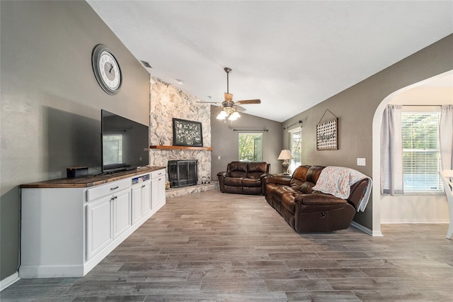 living room featuring dark wood finished floors, a fireplace, baseboards, ceiling fan, and vaulted ceiling