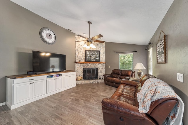 living room featuring a fireplace, light wood-type flooring, ceiling fan, and vaulted ceiling