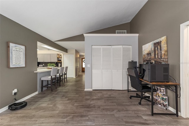 office space with dark wood finished floors, vaulted ceiling, baseboards, and visible vents