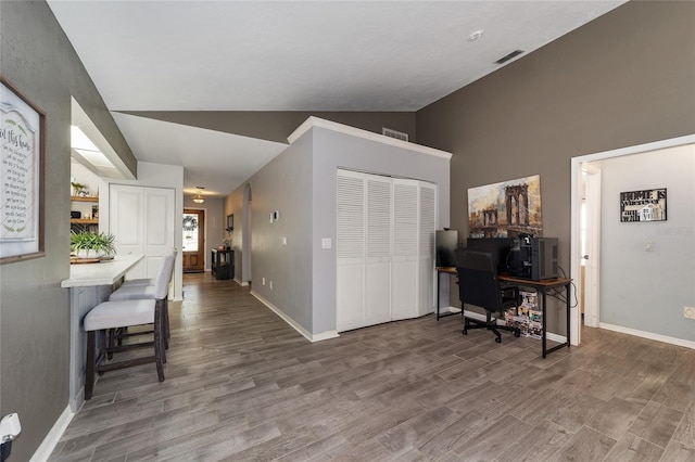 home office with lofted ceiling, wood finished floors, visible vents, and baseboards