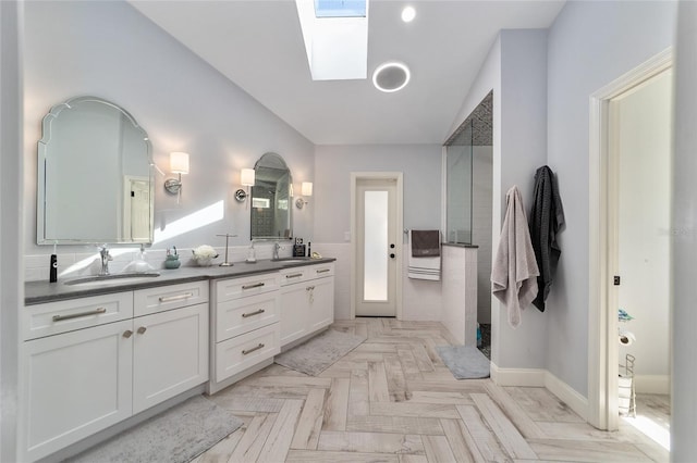 bathroom with double vanity, a skylight, a walk in shower, and a sink