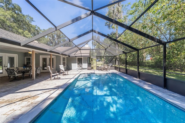 pool with glass enclosure, a patio area, french doors, and ceiling fan