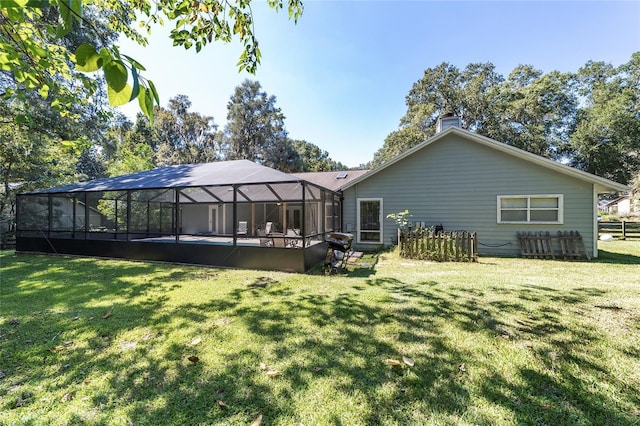 rear view of house featuring an outdoor pool, glass enclosure, a yard, and a chimney