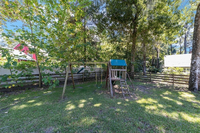 view of playground featuring a lawn and fence