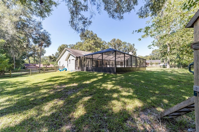 view of yard with glass enclosure and fence