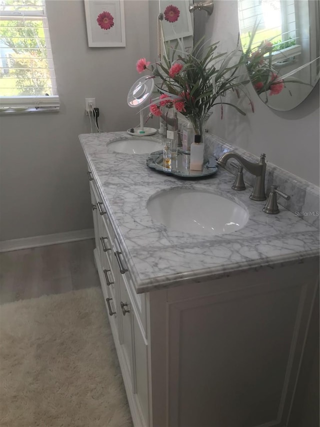full bath featuring double vanity, baseboards, and a sink