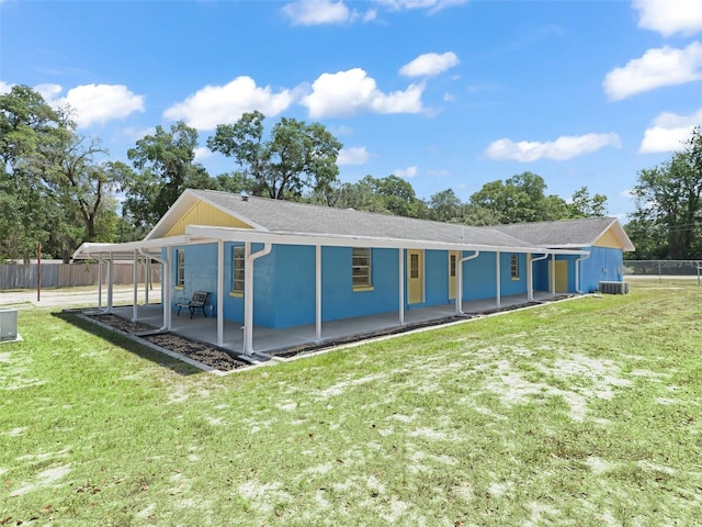 back of property with a patio, fence, central AC, stucco siding, and a lawn