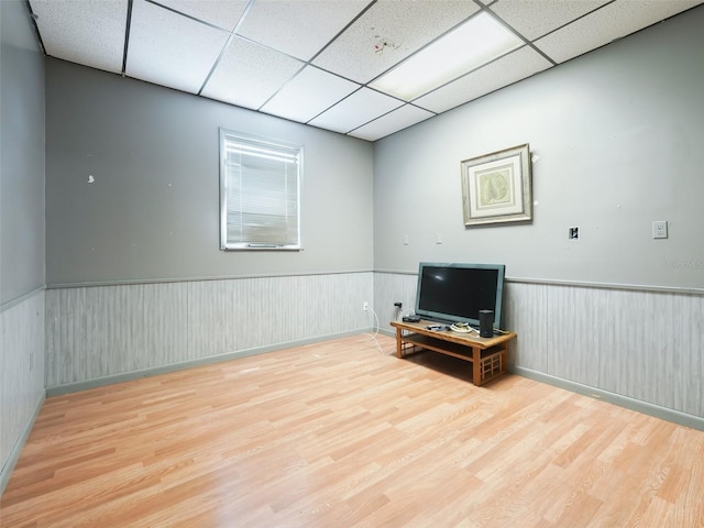 interior space with wood finished floors, a drop ceiling, and wainscoting