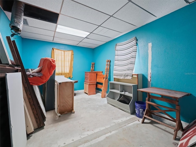 bedroom featuring a drop ceiling and unfinished concrete flooring