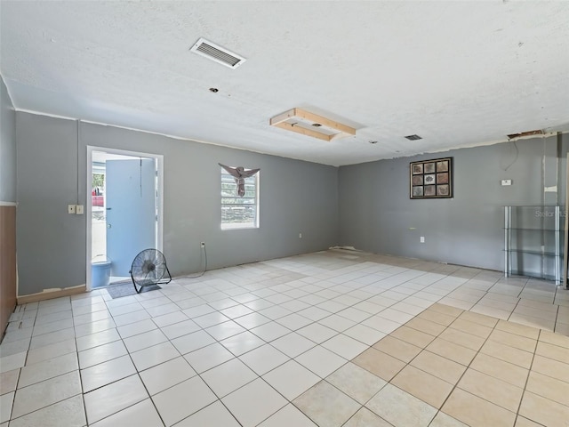 spare room featuring light tile patterned floors, visible vents, and a textured ceiling