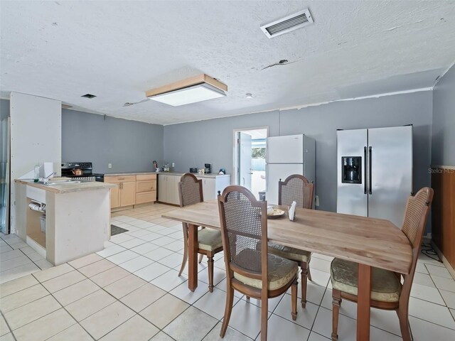 dining area with light tile patterned flooring, visible vents, and a textured ceiling