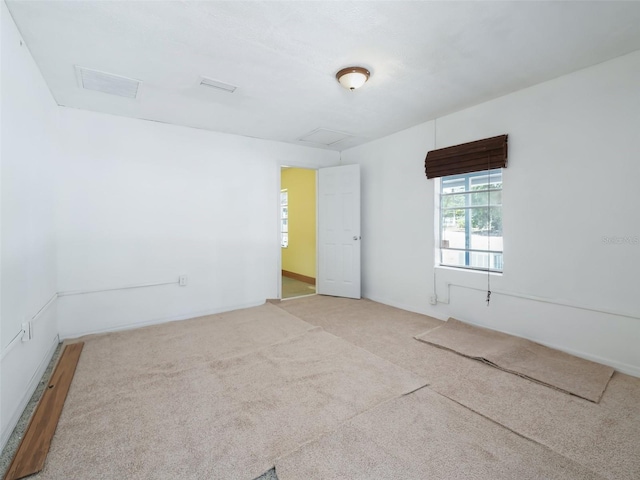 spare room featuring visible vents, attic access, and carpet flooring