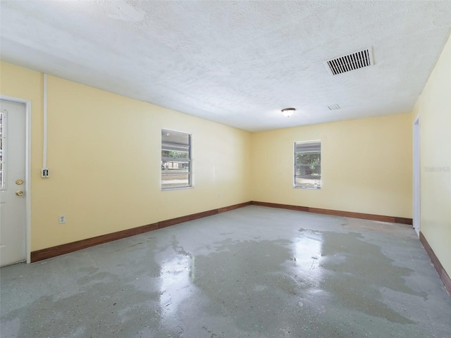 spare room with visible vents, a healthy amount of sunlight, a textured ceiling, and finished concrete floors