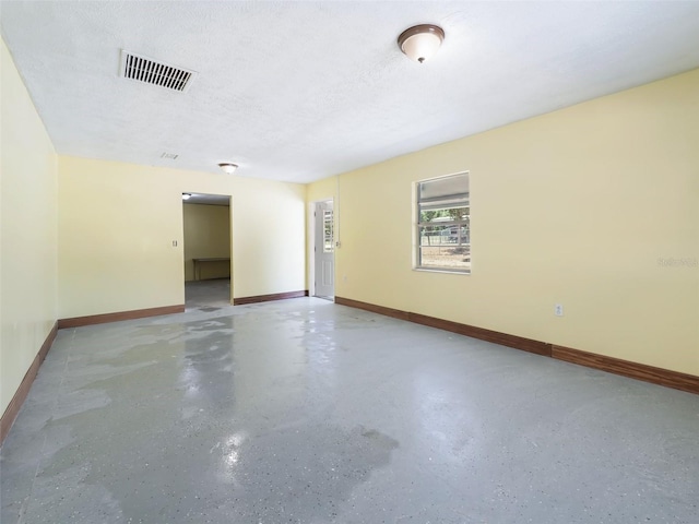 unfurnished room with visible vents, baseboards, and a textured ceiling