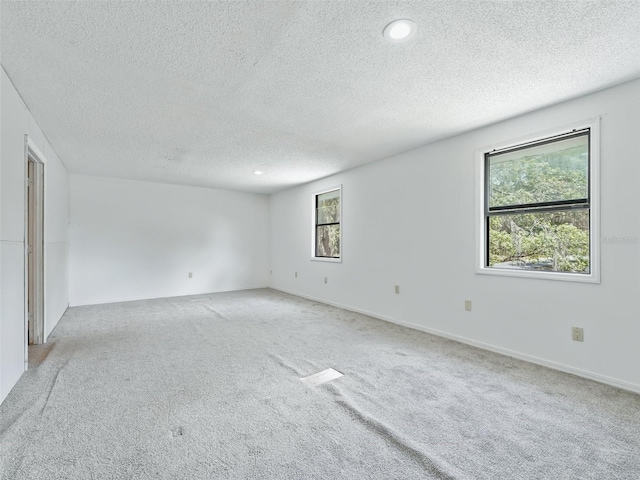 empty room featuring recessed lighting, light colored carpet, baseboards, and a textured ceiling