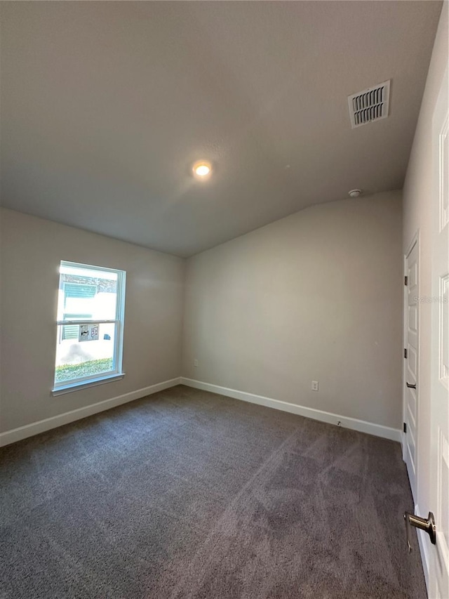 spare room featuring baseboards, visible vents, and dark colored carpet