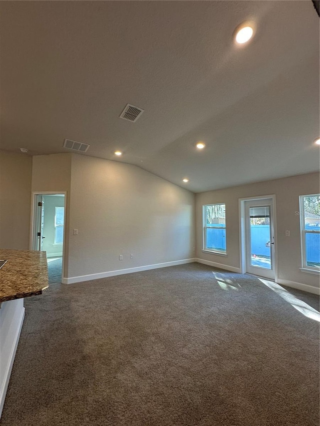 spare room featuring visible vents, baseboards, carpet flooring, and vaulted ceiling