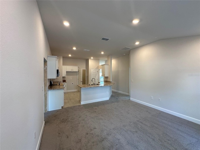 unfurnished living room featuring light carpet, recessed lighting, baseboards, and a sink