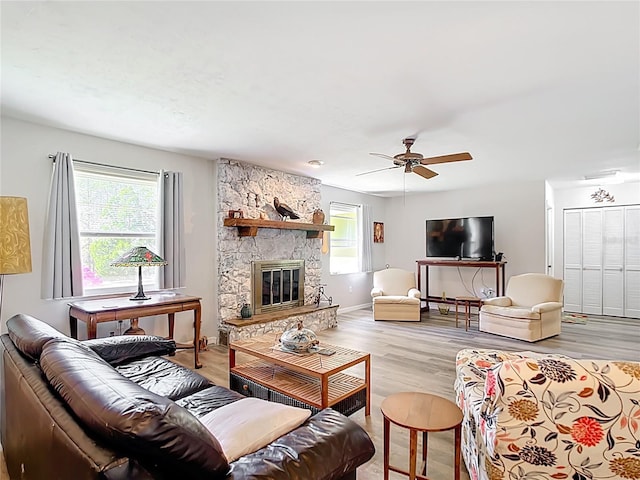 living room featuring a fireplace, baseboards, ceiling fan, and wood finished floors