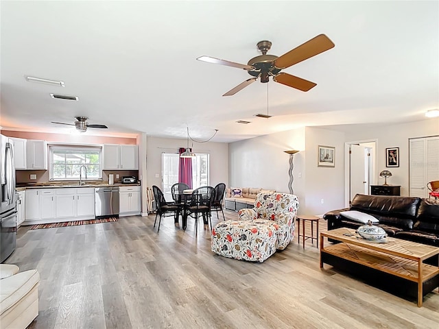 living room with light wood-style flooring, a ceiling fan, and visible vents