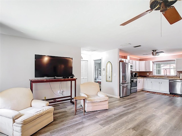 living room with light wood-type flooring, visible vents, and ceiling fan