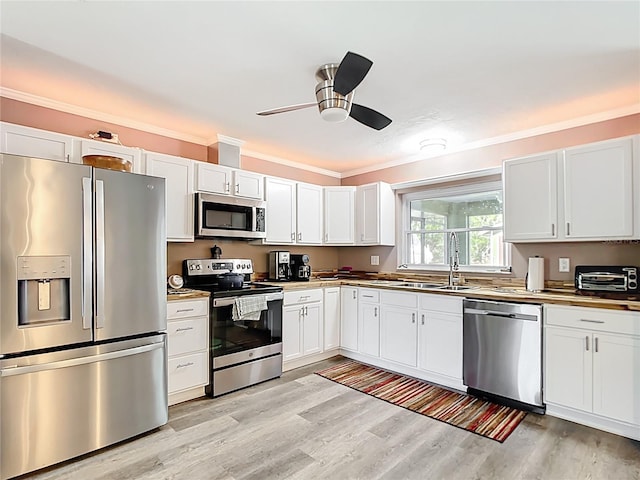 kitchen featuring crown molding, ceiling fan, light wood-type flooring, appliances with stainless steel finishes, and white cabinets