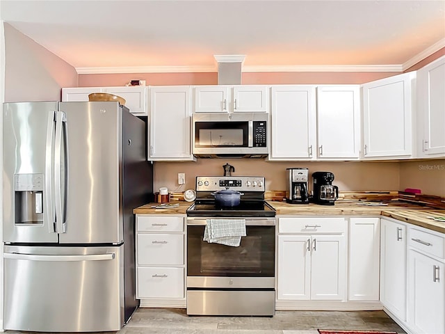 kitchen featuring appliances with stainless steel finishes, white cabinetry, light wood-type flooring, and ornamental molding